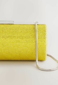 Gul clutch håndtaske lavet af struktureret materiale med cirkulære mønstre; har en sølv kædestrop og metal lukning.