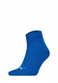 Calcetín azul hasta el tobillo hecho de un tejido suave, con un puño acanalado y un detalle de logo blanco. El diseño es simple y ceñido.