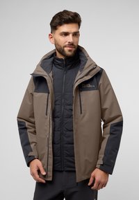 Herenjack met een tan buitenlaag en donkergrijze accenten. Waterdicht materiaal met een ritssluiting, capuchon en gevoerde binnenvoering.