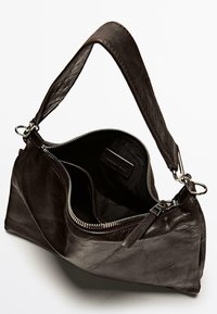 Borsa a mano in pelle nera con una sola tracolla e chiusura con zip. L'interno presenta una fodera in tessuto semplice e un'etichetta. Texture liscia.