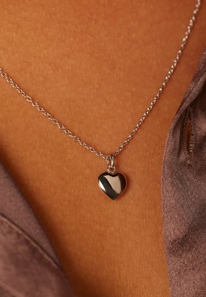 Collier chaîne en argent avec un pendentif en forme de cœur poli. Le cœur est réfléchissant et lisse, avec une boucle simple pour l'attacher.