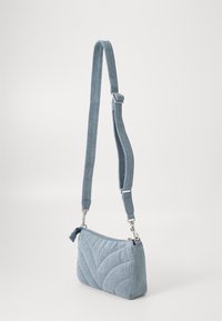 Denim torba za ramena, svetlo modra, kviltana tekstura s cik-cak vzorcem, nastavljiv trak, srebrna kovinska oprema, zadrga na vrhu.