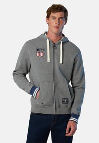 Felpa grigia con zip e toppe degli Stati Uniti, con cordini, tasche frontali e polsini a righe. Realizzata in materiale morbido con una vestibilità casual.