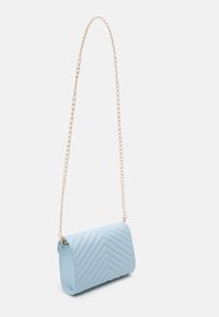 Sac à épaule matelassé bleu clair avec une bandoulière chaîne dorée, de forme cylindrique, avec un motif chevron sur le devant.