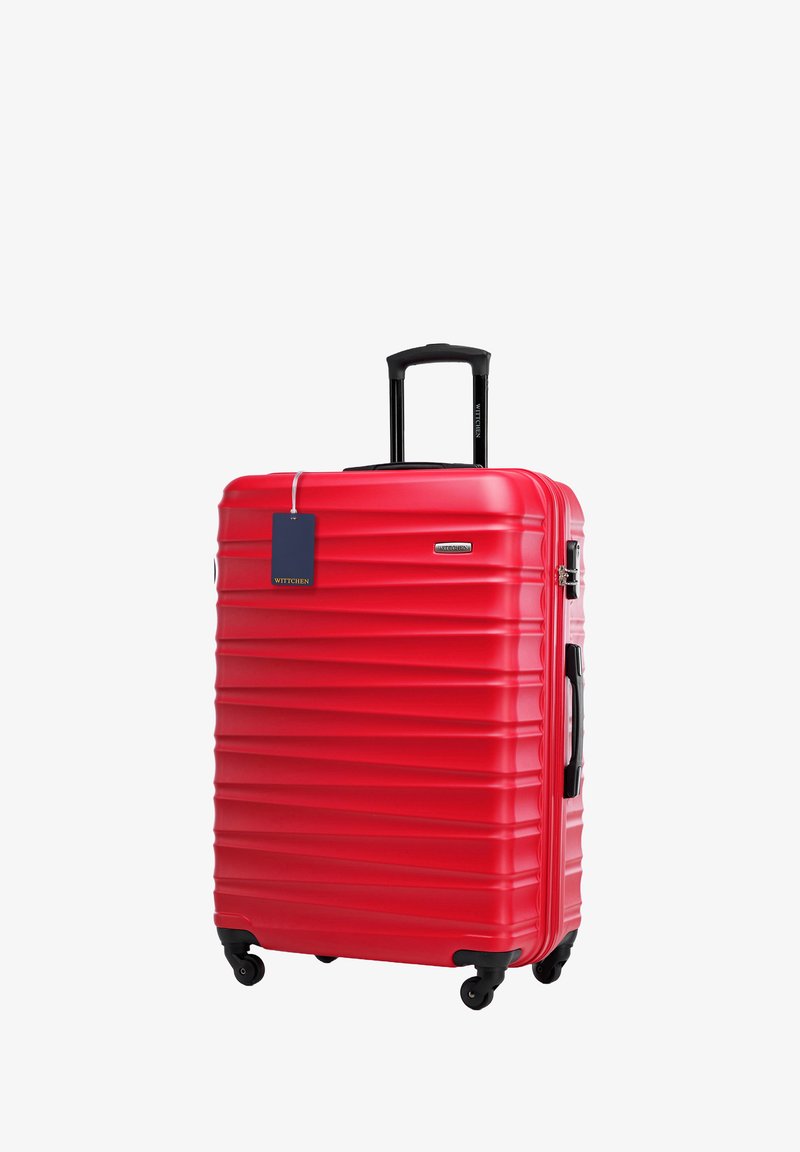 Rode harde koffer met horizontale ribbels, uitschuifbare handgreep, zwarte wielen en een bijgevoegd blauwe prijslabel. Gestroomlijnd ontwerp, duurzaam materiaal.