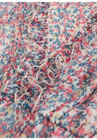 Blumenstoff mit rosa, blauen und gelben Mustern, die mit Rüschensaum und zarter weißer Naht versehen sind, und ein leichtes, strukturiertes Design hervorheben.