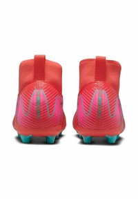 Botas de fútbol rojas y rosas con parte superior suave y texturizada, diseño de tobillo alto y tachuelas turquesas. Presenta el logotipo "Mercurial" en el talón.