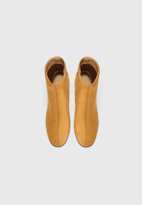 Wüstensandfarbene Wildleder-Stiefeletten mit glatter Textur, seitlichem Reißverschluss und einem schlanken, eng anliegenden Design.