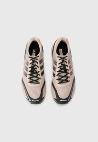 Světle růžové síťované sportovní boty s černými akcenty, které mají tři černé pruhy, černé tkaničky a texturovanou podrážku.