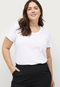 Witte t-shirt met korte mouwen en een ronde hals, gecombineerd met zwarte broek. Het shirt heeft een zachte textuur en een relaxte pasvorm.