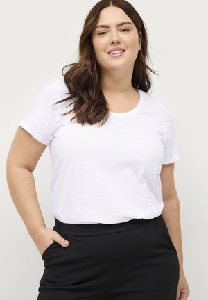 Camiseta blanca de manga corta con escote en forma de drapeado, combinada con pantalones negros. La camiseta tiene una textura suave y un ajuste relajado.