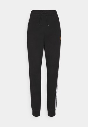 Pantalon jogging noir avec taille élastique et cordon de serrage, bandes latérales blanches avec logo, et chevilles resserrées.