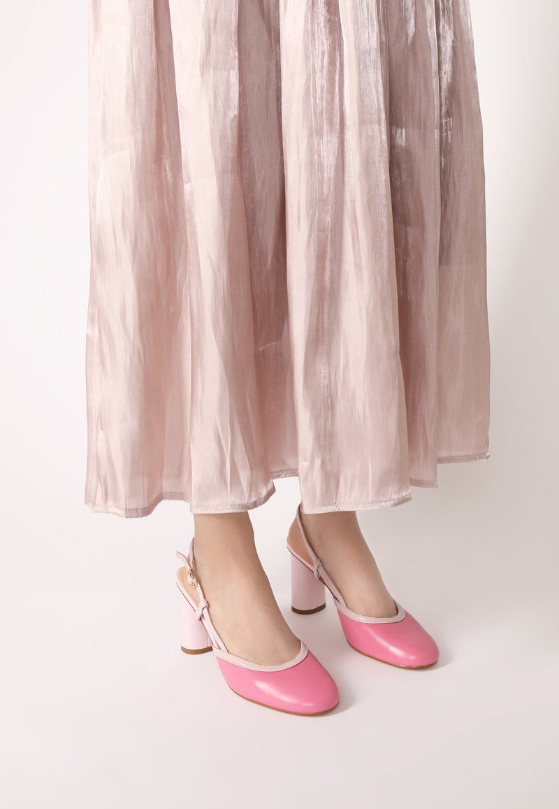 Růžové kožené slingback boty s kulatou špičkou, bílým lemem a růžovými blokovými podpatky, doplněné lehkou roztaženou růžovou sukní.