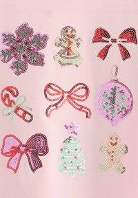 Rosa stof med paljetter i form af peberkager, slikkepinde, sløjfer, snefnug, juledekorationer og et juletræ i forskellige farver.