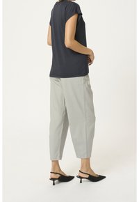 Kortærmet marineblå bluse parret med lysegrå tapered bukser. Sorte slingback sko med spidse tæer. Simpelt design, glat tekstur.