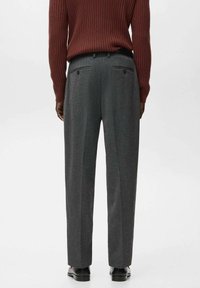 Szare, dopasowane spodnie o prostym kroju, miękkiej fakturze i subtelnym wzorze w kratę; posiadają kieszenie i gładki pas.