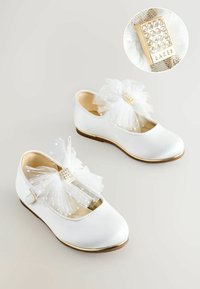 Baltas satīna kurpes ar apaļu purngalu, tām priekšpusē ir liels balts tilla loks un zelta akcentēta kvadrāta forma ar rhinestones.