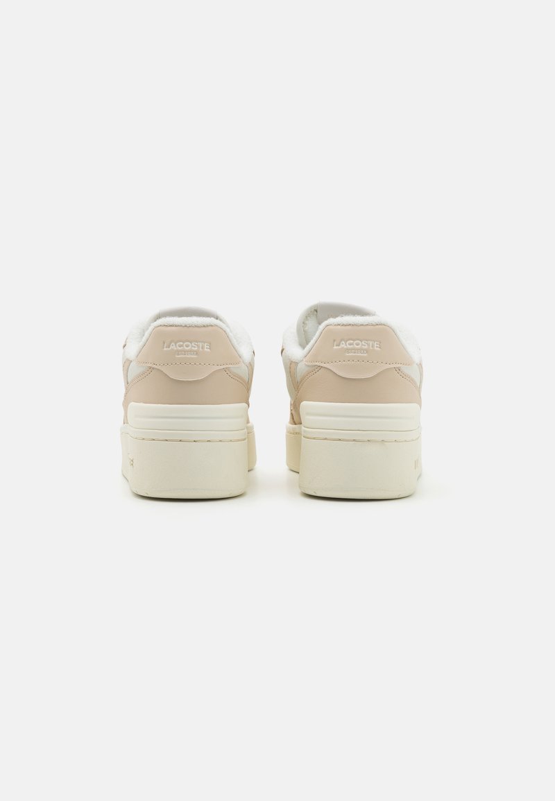Baskets Lacoste avec une tige en cuir beige lisse, un col duveteux blanc et une semelle en caoutchouc crème épaisse. Logo embossé à l'arrière.
