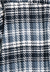 Geruite stof in marineblauw, zwart en wit met een zachte textuur. Bevat een herhalend patroon van vierkanten en lijnen. Geschikt voor warme kleding.