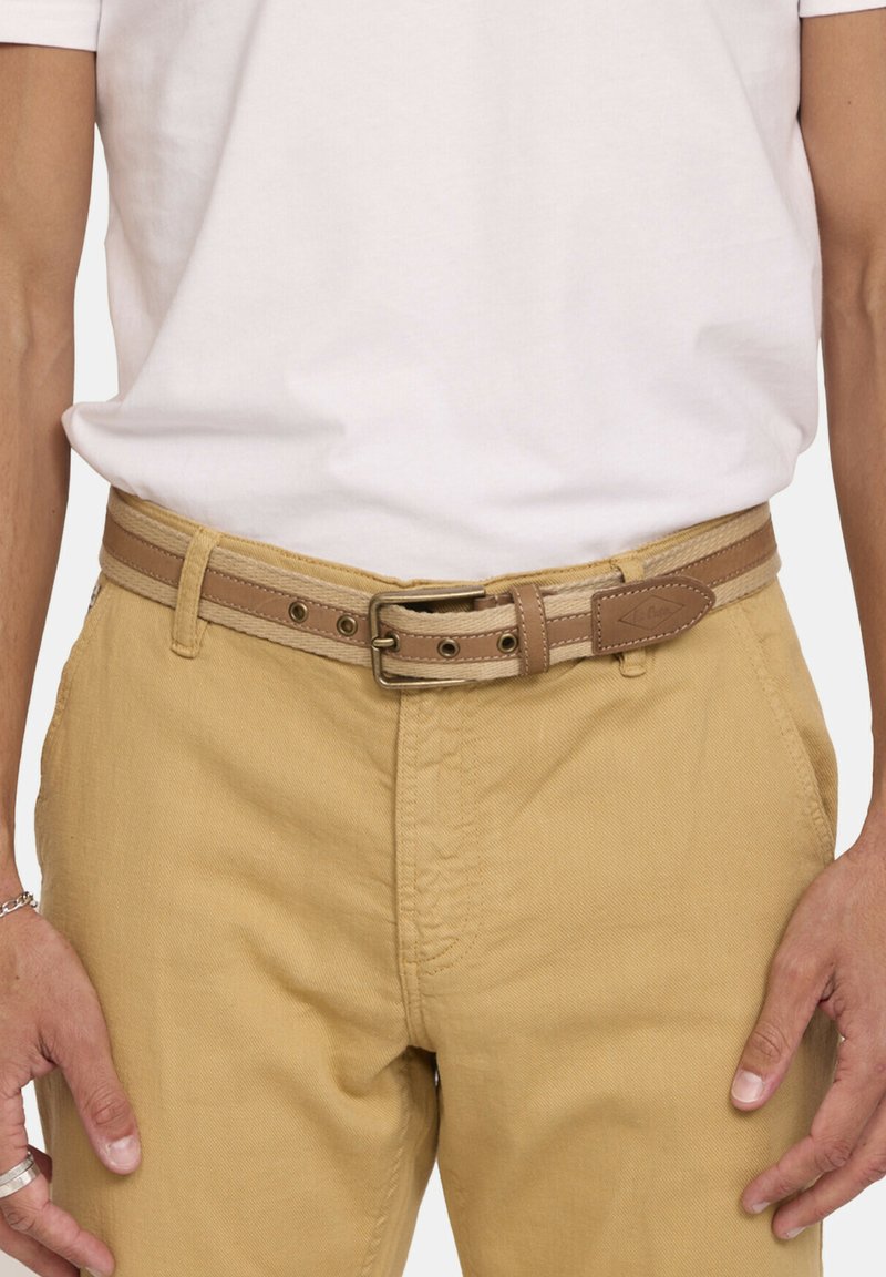 Bruine leren riem met een gestructureerde afwerking, voorzien van een metalen gesp en contrasterende beige stiksels, gedragen over kaki broek.