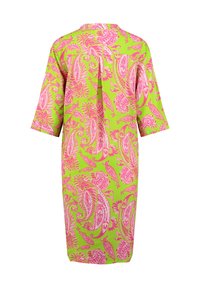 Vestido de manga corta, hasta la rodilla, en una tela verde vibrante con un patrón de flores y paisleys en color rosa. El detalle del pliegue en la parte posterior añade textura.