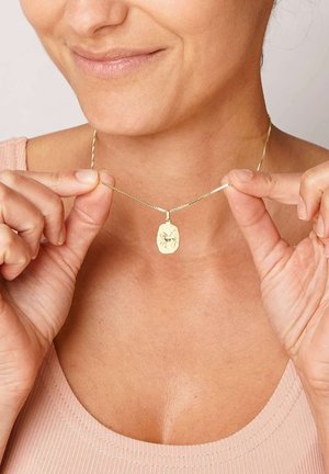 Goldener Anhänger mit einer strukturierten, ovalen Charm auf einer feinen Kette. Der Charm zeigt ein dezentes Design-Detail, das visuelles Interesse hinzufügt.