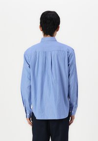 Blue and white striped button-up shirt with long sleeves, a back pleat, and a standard collar. Fabric appears smooth and lightweight.