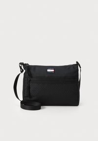 Sac à bandoulière noir en nylon durable avec un motif texturé. Dispose d'une poche zippée à l'avant et d'une sangle réglable. Logo Tommy Jeans visible.