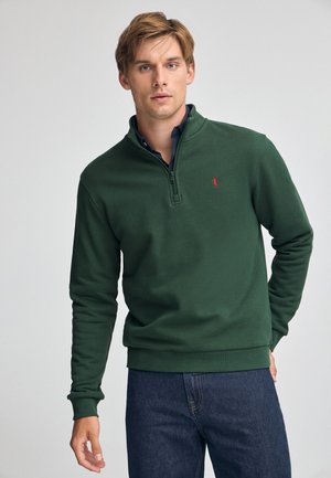 Groene fleece pullover met een hoge kraag, ritsluiting en geribbelde manchetten. Voorzien van een klein rood logo op de linkerborst. Casual ontwerp.