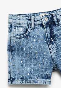Shorts de mezclilla en azul claro con un patrón desgastado, adornados con lentejuelas plateadas distribuidas en la tela y un diseño de cinco bolsillos.