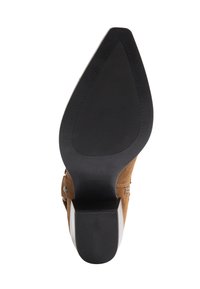 Brązowe zamszowe buty na wysokim obcasie z czarną gumową podeszwą. Charakteryzują się eleganckim wzornictwem i kontrastującym akcentem obcasa. Brak widocznych wzorów lub dodatkowych elementów.