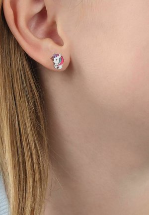 Oreja de un niño con un pequeño pendiente en forma de unicornio con detalles en rosa, púrpura y blanco.