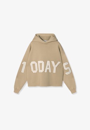 Haut à capuche beige raccourci avec une poche kangourou à l'avant, présentant de grandes lettres blanches en appliqué écrivant "1 0 JOURS" dans une police en gras.