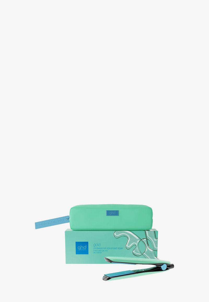 Lisseur à cheveux GHD vert menthe reposant à côté d'une pochette assortie et d'une boîte au design sur le thème des vacances, sur fond blanc.