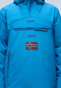 Giacca a pullover blu con tasca sul petto con zip, due tasche laterali e patch della bandiera norvegese. Realizzata in tessuto leggero e liscio.