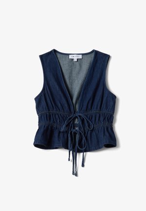 Veste sans manches en jean bleu marine avec un décolleté en V profond, taille élastique et fermeture à nouer devant, suspendue de manière lâche sur fond blanc.