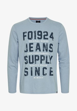 Heled sinise pika varrukaga t-särk, millel on julge must ja valge tekstigraafika, ümar kaelus ja sirge alumine äär.