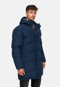 Navy puffer coat featuring a hood, side pockets, and a zippered front. The fabric has a quilted pattern for insulation and warmth.
