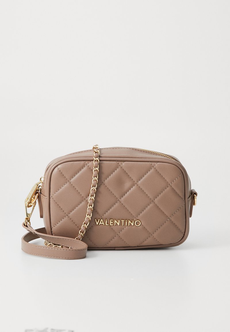 Prešívaná taupe crossbody taška Valentino so zlatým reťazovým popruhom a zipsovým uzáverom, s názvom značky napísaným zlatými písmenami na prednej strane.