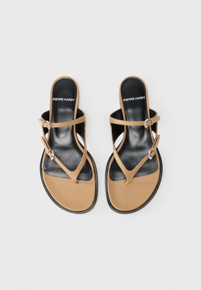 Παντόφλες τύπου flip-flop σε ταμπά χρώμα με ματ φινίρισμα, διαθέτουν δύο λεπτές λουρίδες και λεπτομέρεια με θηλιά. Μαύρη σόλα και λογότυπο στο εσωτερικό παπούτσι.