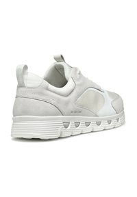 Zapatillas de deporte gris claro que combinan materiales de ante y sintéticos, con una forma redondeada, acentos texturizados y una suela de goma blanca con ranuras.
