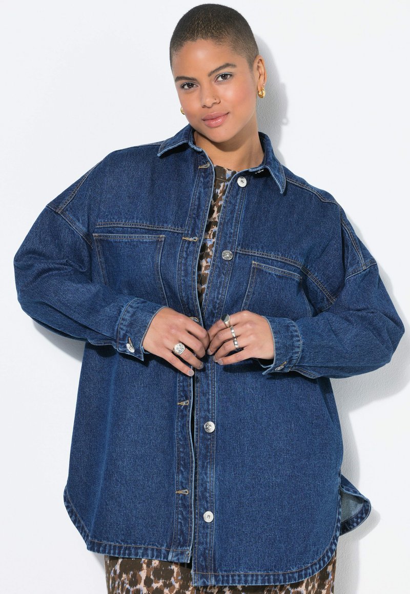 Denimoverskjorta med en avslappnad passform, framträdande knappar och två bröstfickor. Har en klassisk krage och uppvikta ärmar. Mörkblå färg.