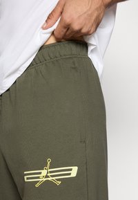 Πράσινο βαμβακερό παντελόνι jogger με ελαστική μέση, με κίτρινο λογότυπο Jordan στο πλάι. Ομαλή υφή και άνετη εφαρμογή.