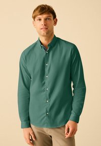 Cămașă cu mâneci lungi, în nuanța solidă de teal, cu guler clasic, având butoane albe și o căptușeală interioară a gulerașului cu un model.