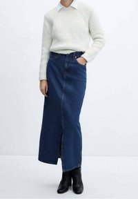 Neulepusero, jossa on kaulus, väriltään kerma; tummansininen farkkumaxihame, jossa edessä halkio ja taskut; mustat nilkkurit.