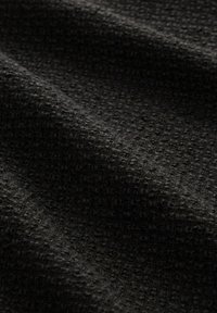 Tissu gris foncé avec un motif texturé étroitement tissé et des plis subtils créant des ombres douces.