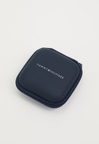 Tumesinine lukuga kott, millel on sile viimistlus ja mille esiosal on selgelt nähtav valge "TOMMY HILFIGER" logo. Kompaktne ja ristkülikuline disain.