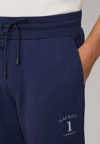 Navy joggers gemaakt van zachte stof, met een elastische tailleband met een koord, zijzak en het 'Hackett London' logo met het nummer één.