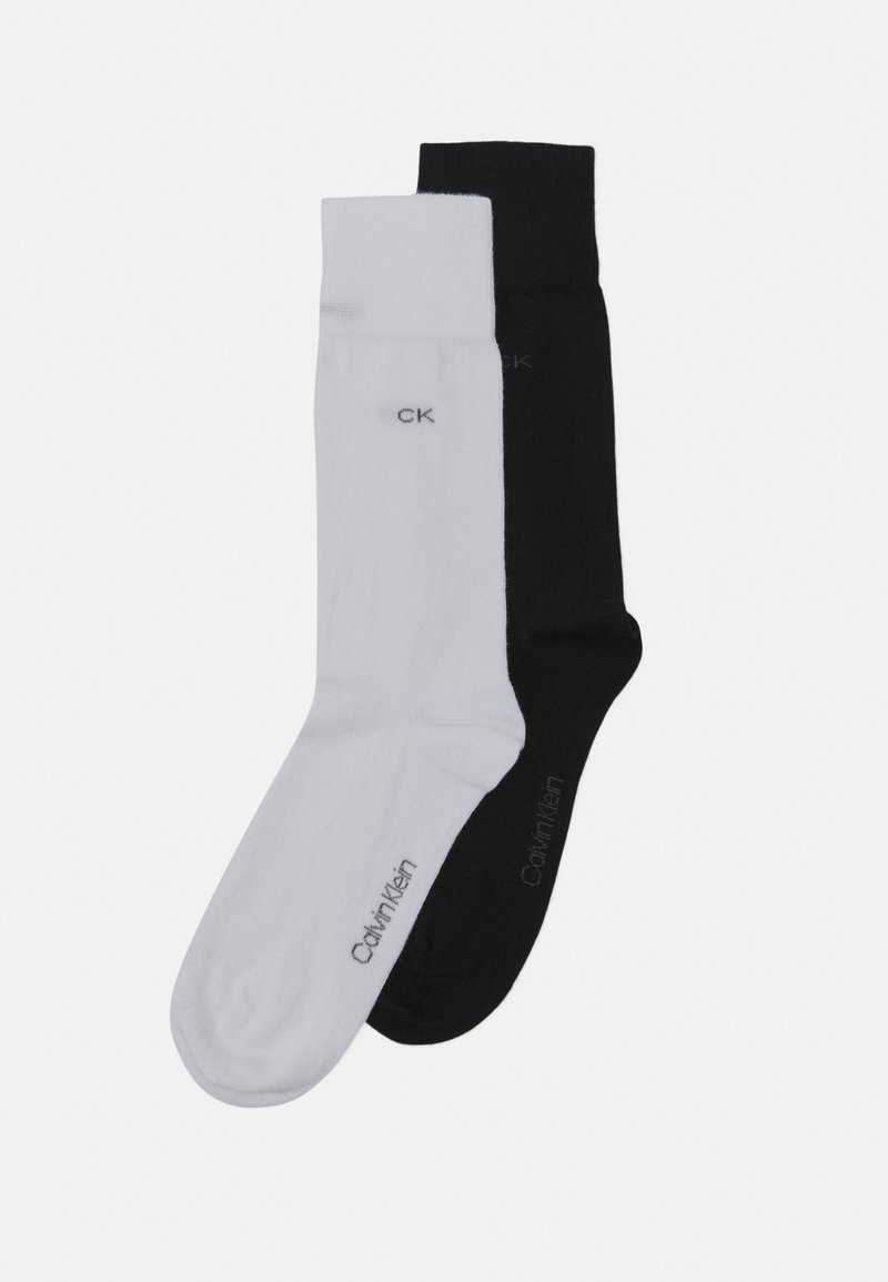 Divas zeķu pāru, viens balts un viens melns, ar minimālistisku dizainu. Katrs zābaks ir ar mazu "CK" logotipu kontrastējošā krāsā.