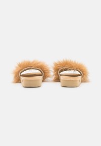 Slides with tan faux fur accents and a light wooden base, featuring an open toe and backless design for easy wear.